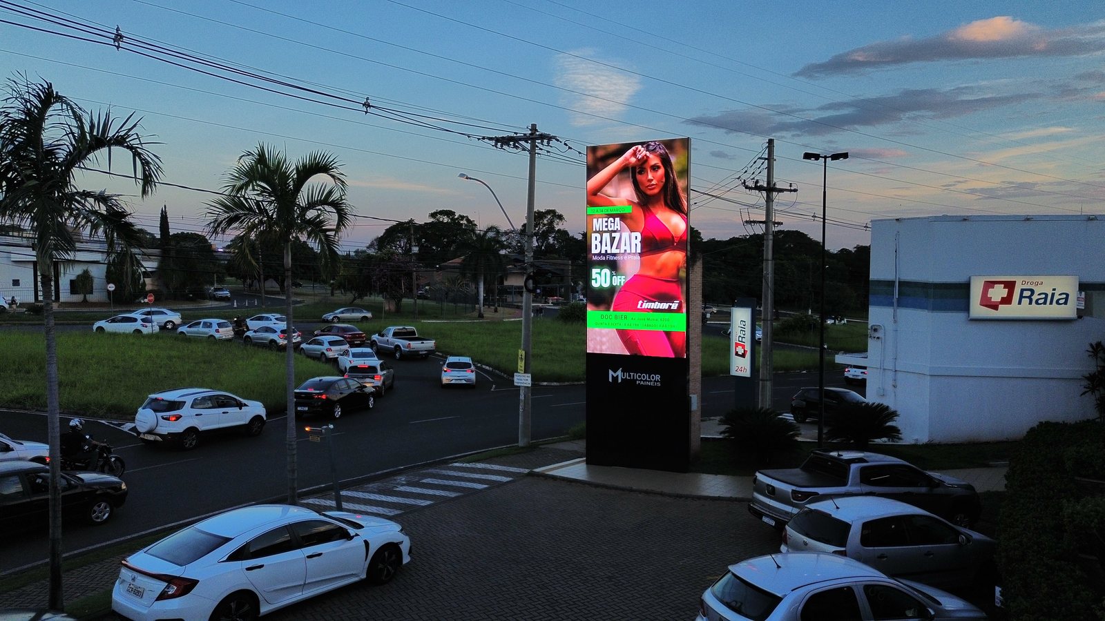 Painel Village Damha ao entardecer com campanha Timborê